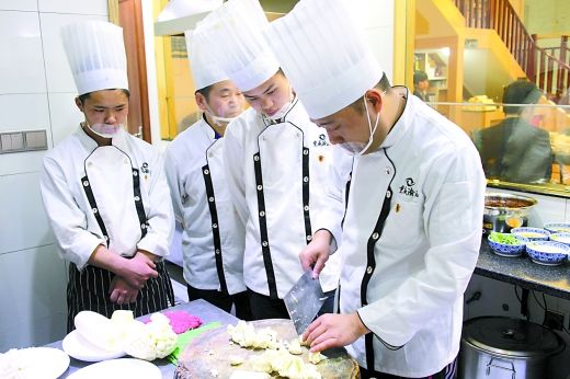 老板曾先生(右一)在厨房与厨师们切磋厨艺。受访者供图